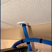 Blue cables passing through a white round port fitted in a ceiling tile